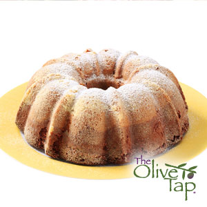 A pumpkin bundt cake sprinkled with powdered sugar on a yellow plate and a white background.