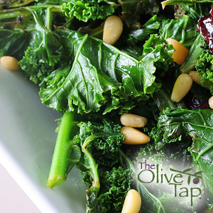 Kale salad topped with pine nuts and served in a white bowl.