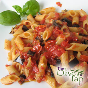 A white plate of penne with a chunky tomato and eggplant sauce garnished with fresh basil leaves.