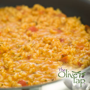 A pan of risotto with tomato chunks, sprinkled with fresh herbs.