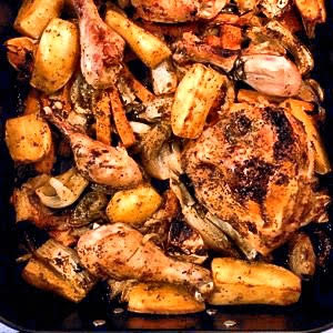 Roasted chicken pieces, potatoes, carrots, and fennel in a pan.