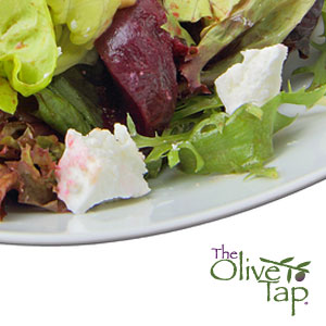 Fresh mixed greens salad topped with roasted beets and crumbled blue cheese, served on a white plate.