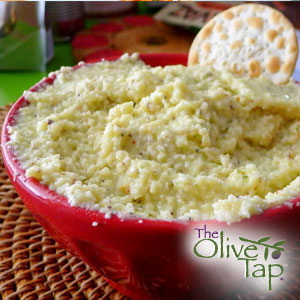 A creamy Parmesan cheese spread, served in a red bowl with a crisp cracker on the side.