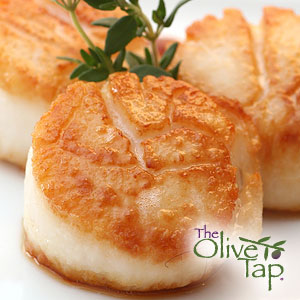 Close-up of pan-seared scallops with a golden-brown crust, garnished with fresh herbs.
