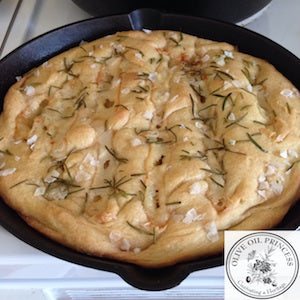 Cast iron pan with fresh baked bread topped with sea salt and fresh rosemary.