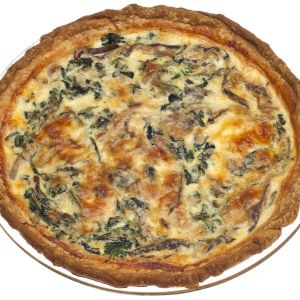 Spinach artichoke quiche baked in a flaky golden crust, featuring a creamy egg filling with spinach, artichoke, and melted cheese, served whole on a white plate.
