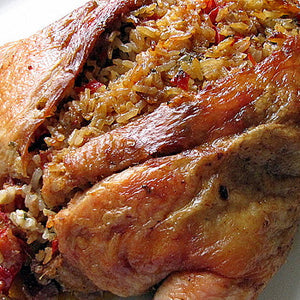 Close-up of a roasted whole chicken stuffed with a wild rice mixture.