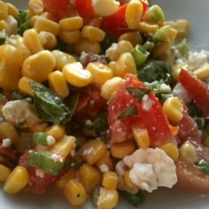 Fresh summer corn and tomato salad made with sweet corn kernels, diced tomatoes, crumbled feta cheese, fresh basil, green onions, and fresh herbs, tossed in a light dressing.