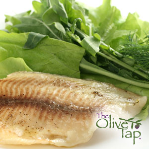 Baked tilapia fillet with a light golden crust, served alongside fresh leafy greens and herbs on a white plate.