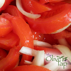 A close-up of sliced tomatoes and sliced white onions mixed together.