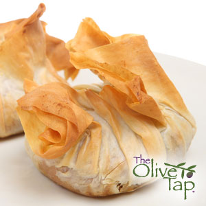 Crsipy puff pastry folded into a "purse" stuffed with vegetables on a white plate.
