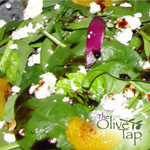 Spinach salad with red onion, mandarins, and cheese crumbles, drizzled with a dark chocolate balsamic vinegar.