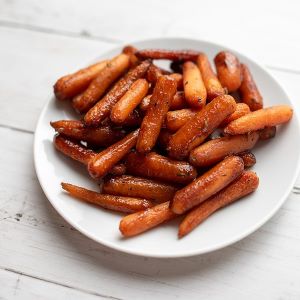 Roasted carrots coated in a balsamic glaze and served on a white plate.