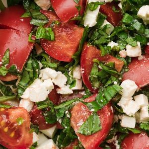 A tomato salad topped with feta cheese and fresh chopped basil.