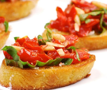Sliced bread topped with bruschetta and chopped basil.