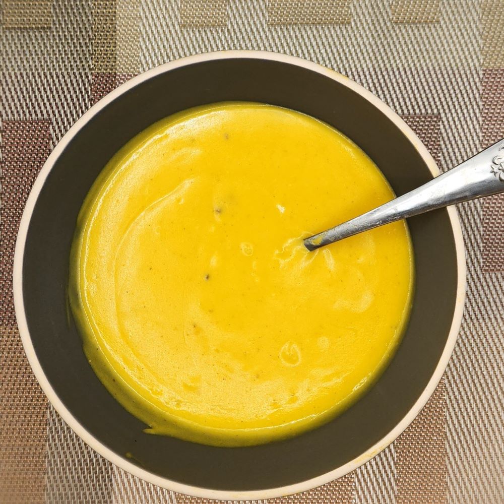 Butternut squash and pumpkin soup with a creamy texture served in a bowl with a spoon.
