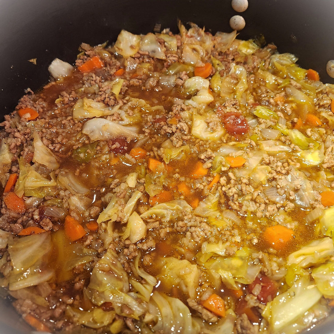 Cabbage soup with cabbage chunks, ground beef, and carrots in a pot.