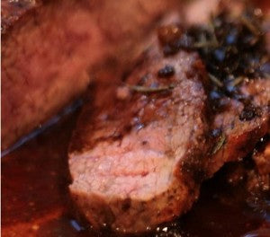 A sliced steak with a seared crust and balsamic glaze.