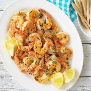 Seasoned shrimp served with lemon pieces on a white serving dish.