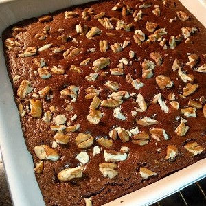 A baking dish of fresh-baked brownies topped with chopped walnuts.