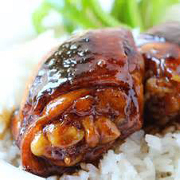 A close-up of honey balsamic glazed chicken thighs served on a bed of rice.