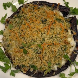 A portobello mushroom stuffed with breadcrumbs, shredded carrots, and zucchini garnished with fresh parsley.