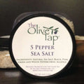 5 Pepper Sea Salt from The Olive Tap: A jar with a white label that includes The Olive Tap logo with an olive branch, product name, and ingredients list, with the jar in front of a gray background.