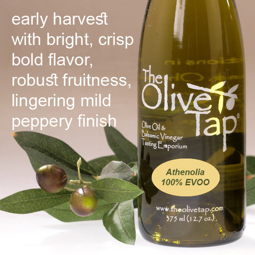 A bottle of Athenolia 100% Extra Virgin Olive Oil from The Olive Tap with olives and leaves including text describing the olive oil flavor profile on a light background.
