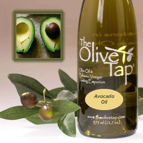 A bottle of Avocado Oil from The Olive Tap next to olives and leaves with an inset showing a fresh halved avocado.