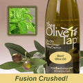 A bottle of The Olive Tap Basil Olive Oil next to olives and leaves with an inset showing a fresh basil on a light background with the words "fusion crushed!" at the bottom of the picture.