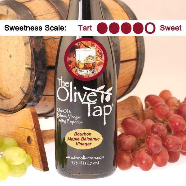 A bottle of Bourbon Maple Balsamic Vinegar from The Olive Tap with a picture of a glass of bourbon and maple leaves, surrounded by grapes in front of a wooden barrel, and a sweetness scale indicating a four on a light background.