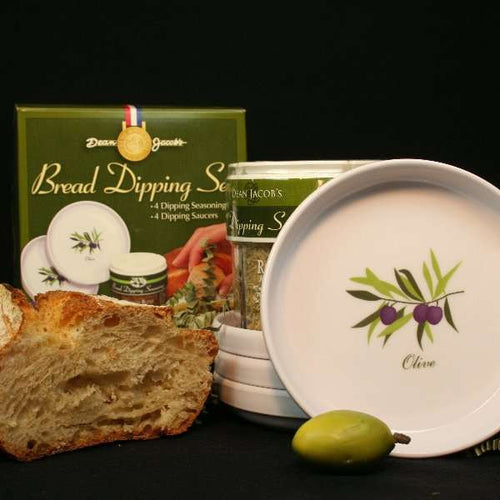 Bread Dipping Seasoning and Saucer Set from The Olive Tap: A stack of bread dipping saucers, a loaf of bread, packet of dipping sauce seasoning, a jar of bread dipping seasoning, and an olive on a black background.