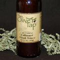 A bottle of Cabernet Steak Sauce from The Olive Tap with green decorative crinkle paper against a black background and surface.
