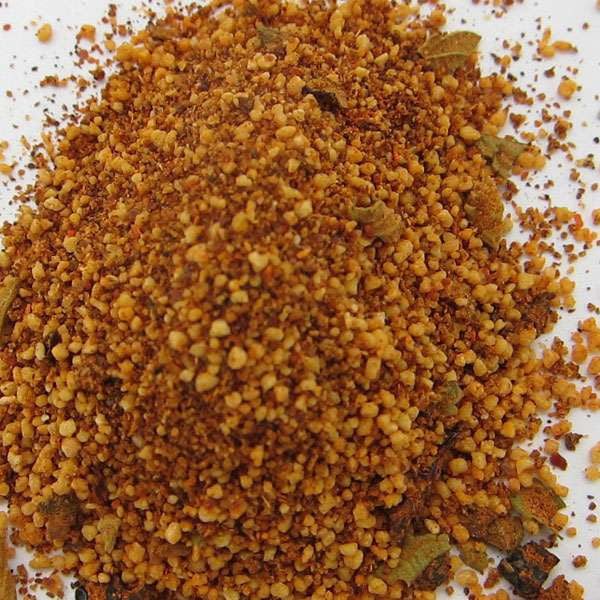 Chipotle Barbeque Seasoning from The Olive Tap: A pile of tan and red seasoning of different sizes on a light background.