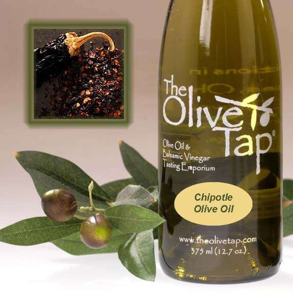 A bottle of Chipotle Olive Oil from The Olive Tap with olives and leaves with an inset showing a whole chipotle pepper next to a pile of crushed pepper.