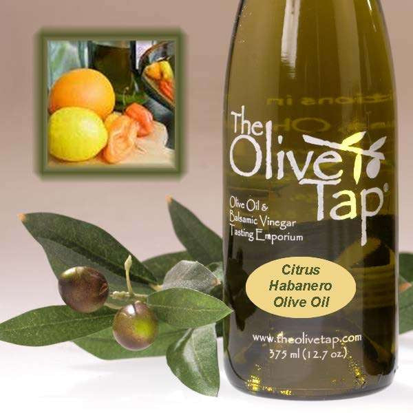 Bottle of The Olive Tap Citrus Habanero Olive Oil next to olives and leaves with inset of citrus fruits and habanero peppers on a light background.