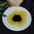 Pinzimonio Olive Oil Dipping Dish - Cloud Design from The Olive Tap with olive oil and vinegar inside and a slice of bread with grapes and olive leaves in the background.