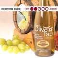Coconut Pineapple White Balsamic Vinegar from The Olive Tap with grapes in front of a wooden barrel with a picture of a coconut and pineapple inside, and a scale indicating a sweetness of wo.