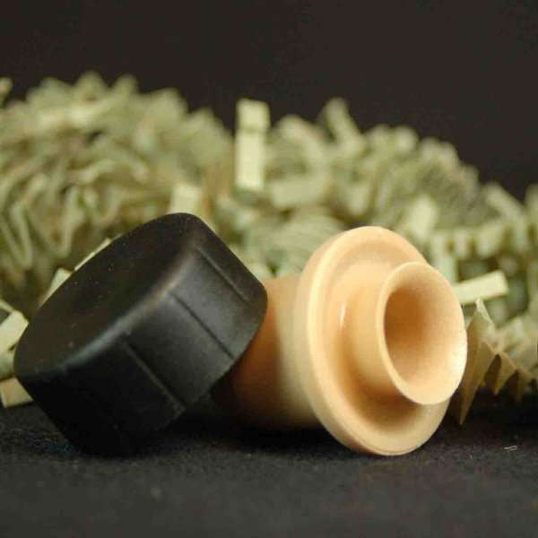 Dripless Cap & Pour Spout from The Olive Tap, cream and black in color with decorative crinkle paper on a black background and surface.