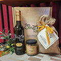 Focaccia Bread Baking & Dipping Kit with Extra Virgin Olive Oil from The Olive Tap: A bottle of extra virgin olive oil, bread dipping herbs, focaccia bread mix in front of a decorative Olive Tap box and olives with leaves next to it.