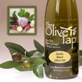 A bottle of Garlic Basil Olive Oil from The Olive Tap next to olives and leaves with an inset showing bulbs of garlic and fresh basil leaves.