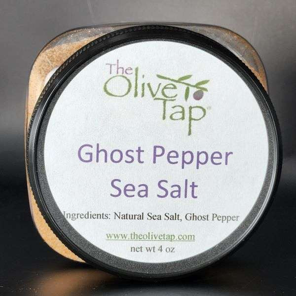 Ghost Pepper Sea Salt in a jar from The Olive Tap with a white label that includes The Olive Tap logo with an olive branch, product name and ingredients list with the jar in front of a gray background.