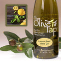 A bottle of Lemon Basil Olive Oil from The Olive Tap next to olives and leaves with an inset showing lemons and fresh basil on a light background.