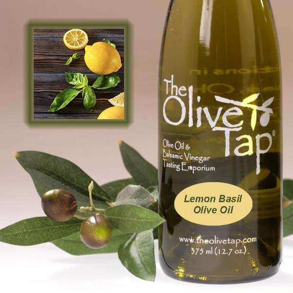A bottle of Lemon Basil Olive Oil from The Olive Tap next to olives and leaves with an inset showing lemons and fresh basil on a light background.