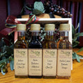 Olive Tap Little Italy sampler: Two olive oil and two vinegar bottles in front of a wooden crate with a bow and purple grapes in the background.