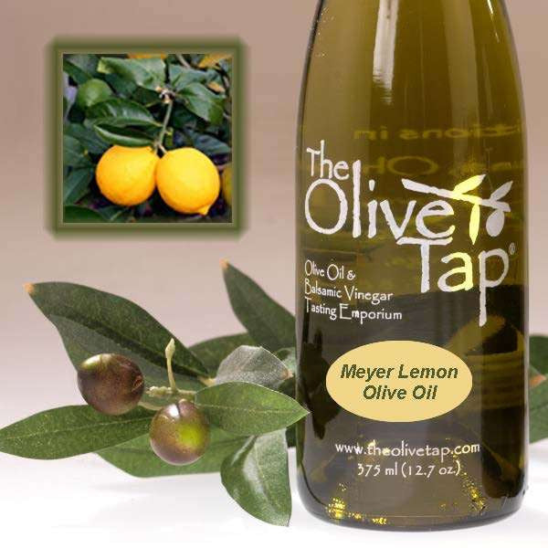 A bottle of Meyer Lemon Olive Oil from The Olive Tap next to olives and leaves with an inset showing meyer lemons on a light background.