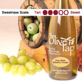 A bottle of Pear White Balsamic Vinegar from The Olive Tap surrounded by grapes in front of a wooden barrel with a picture of pears inside, and a sweetness scale indicating a three on a light background.
