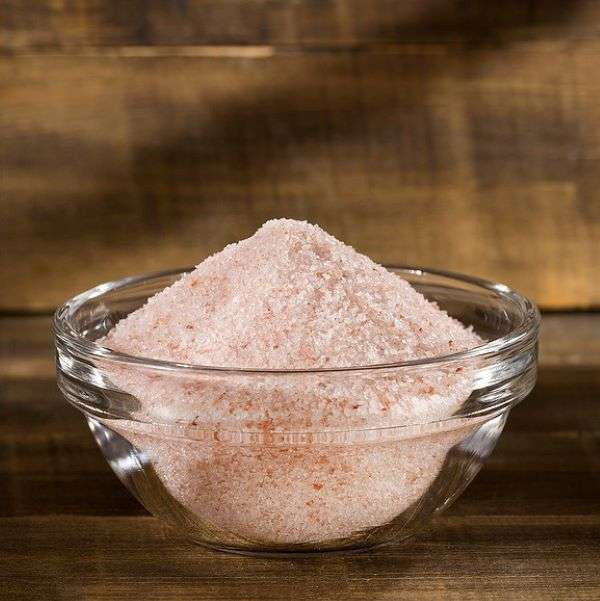 Pink Himalayan Salt from The Olive Tap in a clear glass bowl on a wooden surface.