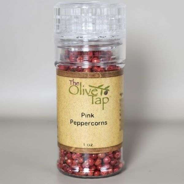 Pink Peppercorns In Grinder Jar from The Olive Tap with The Olive Tap logo and olive branch against a light-colored background.