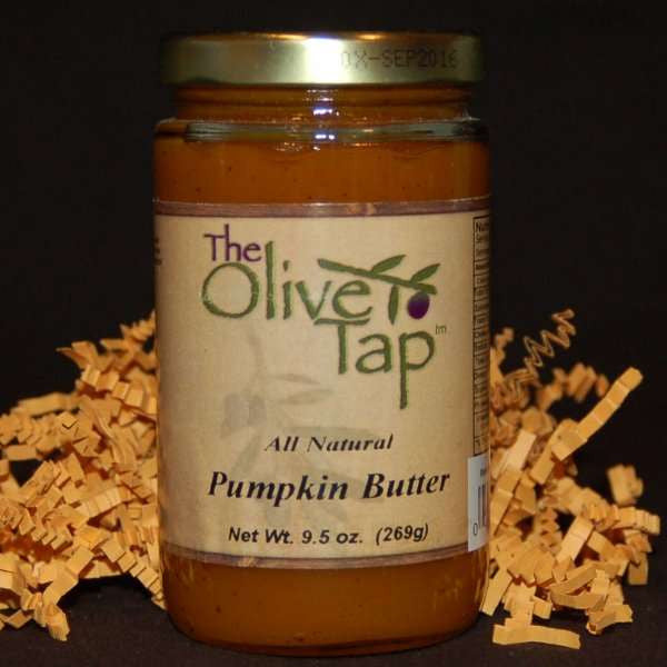 A jar of Pumpkin Butter from The Olive Tap, surrounded by decorative orange crinkle paper.